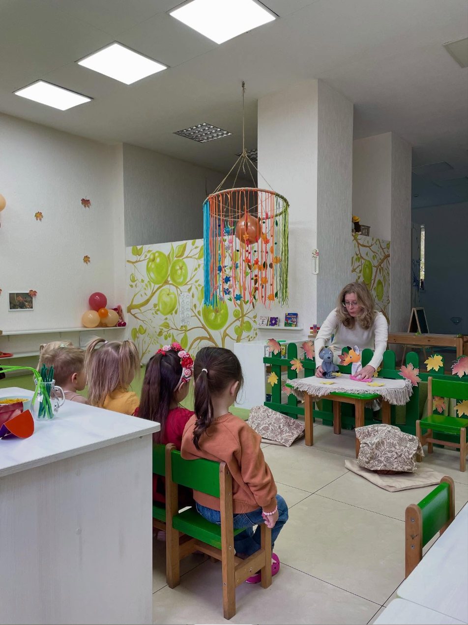 Групова кімната KidsCan: столики, розпис із яблуками, заняття з педагогом
